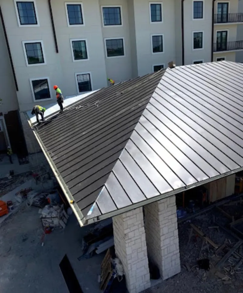 Crew installing standing seam metal roof panels on a commercial project in George Mason
